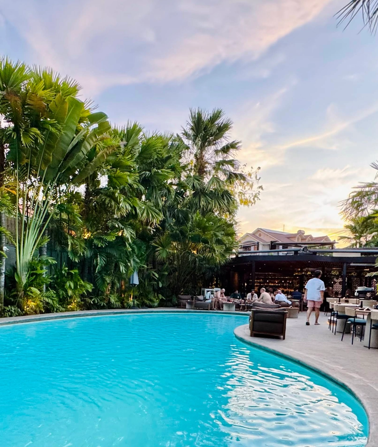 Poolside seating at Brix at golden hour, palm silhouettes against a pastel sunset sky