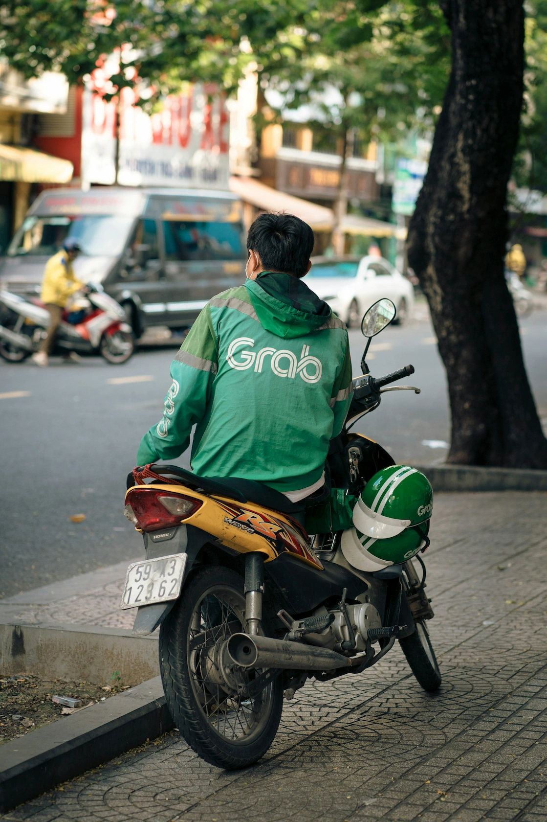 Grab motorbike driver waiting on a Saigon curb