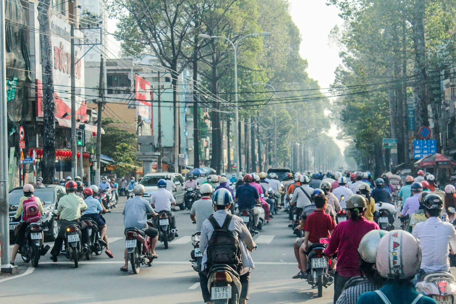 Rush hour motorbike traffic on a tree-lined Saigon boulevard