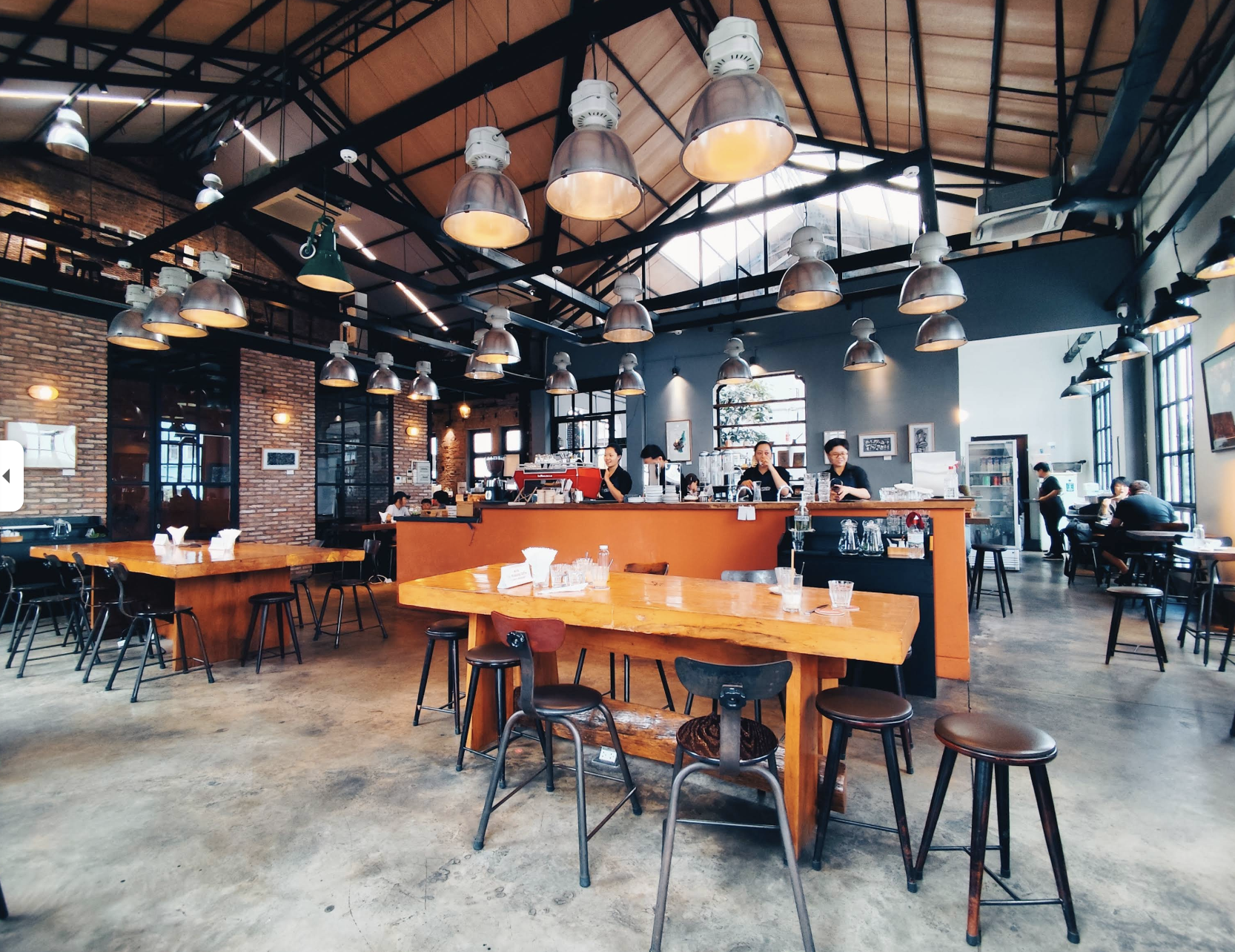 The Workshop coffee roaster interior with industrial pendants, brick walls, and live-edge wood tables